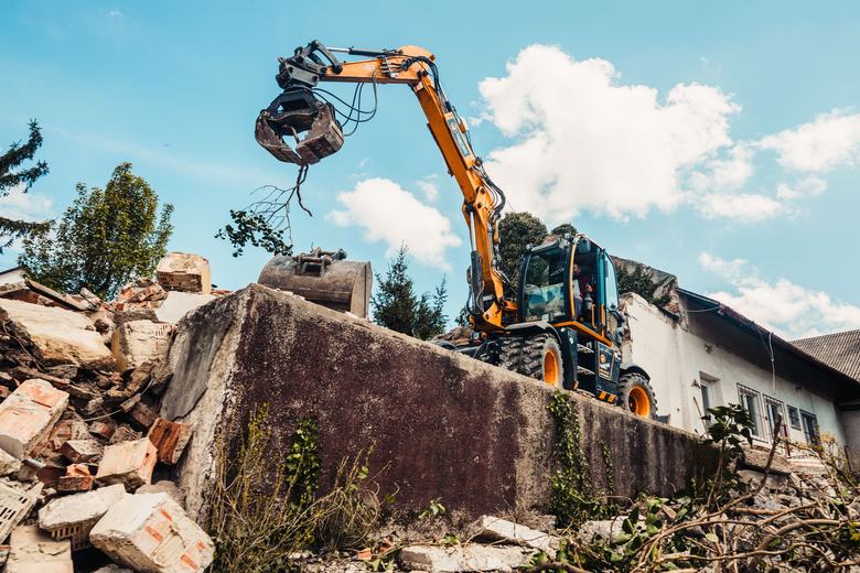 Pelle de démolition avec pince devant un mur en ruine